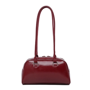 Detail of burgundy oil wax leather texture and silver hardware on shoulder bag