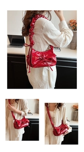 Detail view of the bright red pleated shoulder strap and knotted design on a handbag