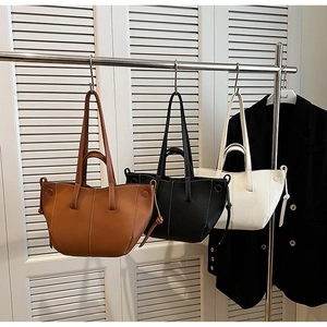 Detail of pleated tote bags in caramel black and beige with contrast stitching