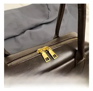 Détail du sac en cuir marron foncé avec double fermeture éclair et finitions dorées