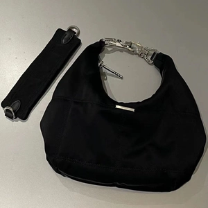 Black nylon crescent hobo bag with silver chain handle and detachable strap on gray background