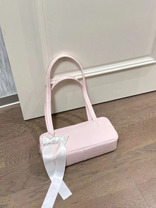 Detail of light pink shoulder bag with a large white decorative bow on side