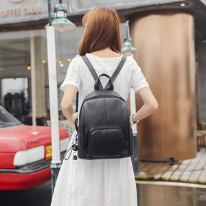 Chic black soft leather backpack for women with cute bear pendant in street fashion scene