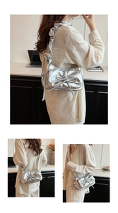 Close-up of silver metallic shoulder bag with bow detail and trendy ruched strap design
