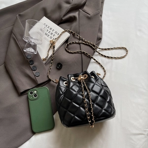 Detail of black quilted bucket bag featuring a drawstring closure and gold chain strap