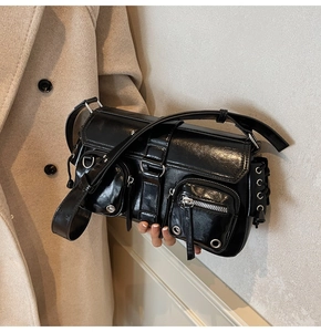 Detail of black glossy cool-girl shoulder bag with multi-pocket and metal hardware