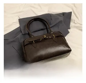 Détail du sac Boston marron foncé avec boucle dorée et texture en cuir ciré de style rétro