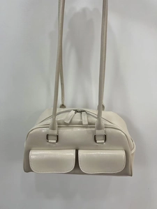 Detail of cream glossy leather bag featuring double front flap pockets and slim shoulder straps