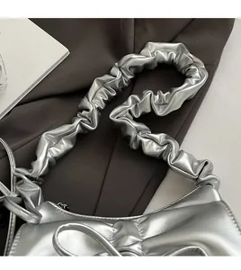 Close-up of the silver pleated elastic scrunchie strap on a metallic shoulder bag