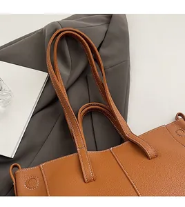 Detailed view of brown lychee leather tote bag with white contrast stitching and dual straps