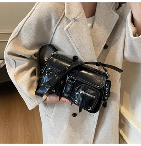 Detail of glossy black motorcycle shoulder bag with multi-pockets and metal hardware