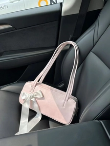 Close-up of pink bow shoulder bag on car seat with natural sunlight and shadow