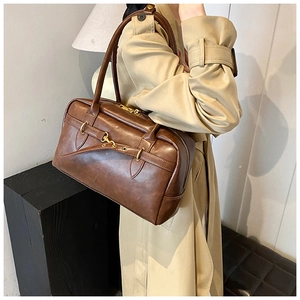 Détail d'un sac Boston vintage marron avec finitions dorées et texture cuir mat élégante