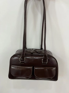 Detail of dark brown oil wax leather shoulder bag with glossy finish and front pockets
