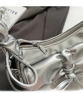 Detail of silver pleated cloud bag showing smooth metal zipper and metallic leather texture