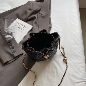 Close-up of quilted black leather bucket bag with star-shaped opening and gold chain strap