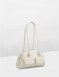 Close-up of cream wax leather bowling bag featuring double front flap pockets and slim handles