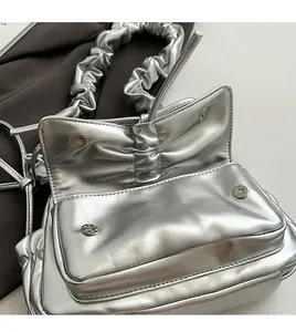 Macro detail of silver pleated cloud bag featuring magnetic closure and metallic leather texture