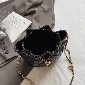Top view of black quilted leather bucket bag with gold chain and soft interior space