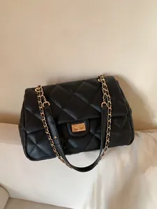 Close-up of black quilted leather bag featuring gold twist lock and chain strap detail