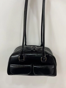 Detail of glossy black oil wax leather bowling bag featuring double pockets and metallic buckles