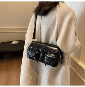 Detail of black glossy multi-pocket shoulder bag on model with silver metal hardware