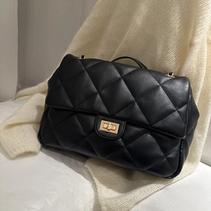 Close-up of black quilted leather handbag with golden twist-lock and fine texture