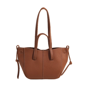 Detail of brown leather tote bag showing lychee grain texture and contrast stitching