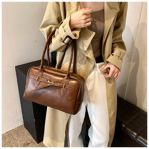 Gros plan du sac Boston vintage en cuir marron avec anneaux dorés et doubles poignées