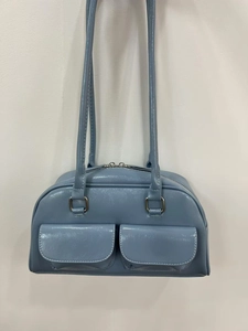 Detail of blue glossy oil wax leather bowling bag with double front pockets and gold hardware