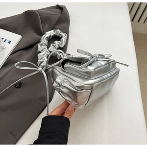Close-up of silver pleated cloud bag with metallic finish and bow ribbon detail