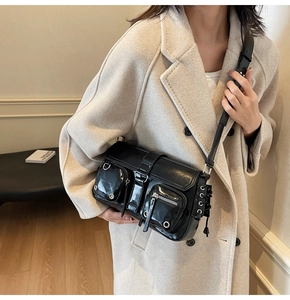 Detail of black glossy leather armpit bag with functional pockets and silver hardware