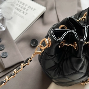 Close-up of black quilted bucket bag featuring gold chain strap and luxury hardware