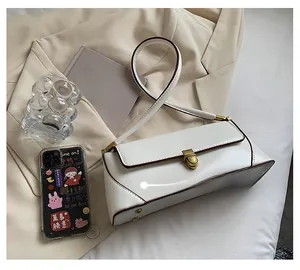 Detail view of white underarm bag with vintage gold lock buckle and brown edge oil