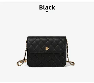 Détail du sac en cuir matelassé noir avec fermoir fleur dorée et bandoulière chaîne