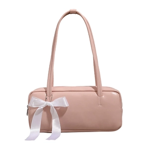 Detail of light pink baguette bag featuring a large white satin bow on the shoulder strap
