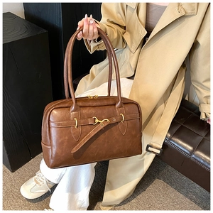 Gros plan du sac Boston vintage marron foncé avec boucle mors dorée et longues anses élégantes