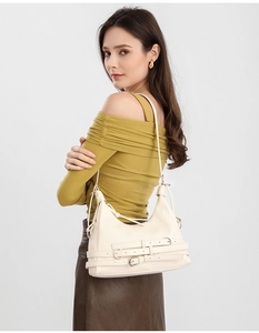 Gros plan d'un sac sous le bras en cuir crème avec des boucles argentées décoratives