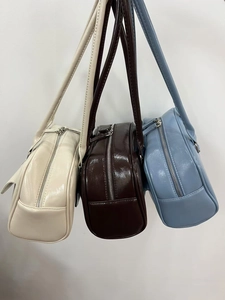 Close-up of sleek oil wax leather bowling bags in white, dark brown, and blue colors