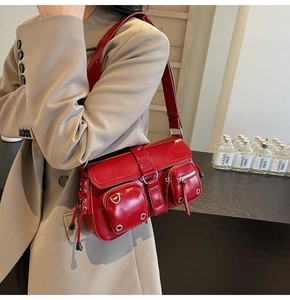 Detail of red faux leather shoulder bag with multi-pocket design and glossy finish