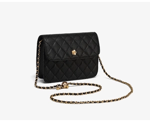 Détail du sac en cuir matelassé noir avec fermoir fleur de camélia doré et bandoulière chaîne