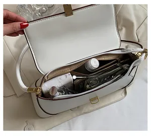 Detail view of white shoulder bag with multi-layer compartments and gold metal buckle