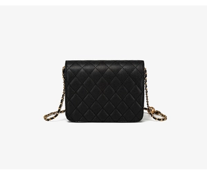Détail d'un sac bandoulière matelassé noir avec chaîne dorée et bille décorative