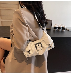 Detailed side view of white crescent bag with glossy finish and retro metal buckles