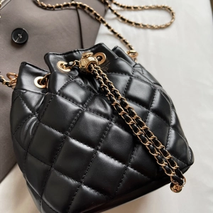 Close-up of black quilted bucket bag with golden drawstring bead and chain strap