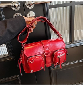Detail of red faux leather shoulder bag featuring multiple pockets and silver hardware