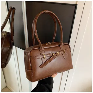 Détail d'un sac porté épaule vintage en similicuir marron avec boucles en métal doré poli