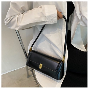 Detail of black leather underarm bag with golden metallic clasp on a white shirt
