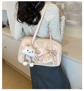 Detail of light pink patent leather tote bag with bow pockets shown on shoulder