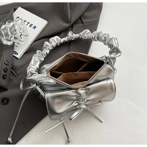 Detail view of the silver metallic ruched bag showing the brown fabric interior and pockets